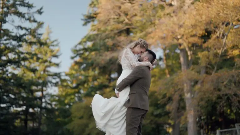 One newlywed lifting their partner among autumn trees.
