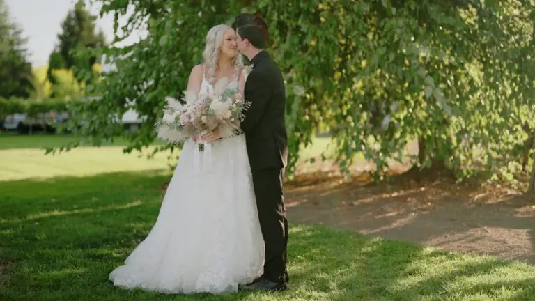 Newlyweds standing beneath a leafy tree