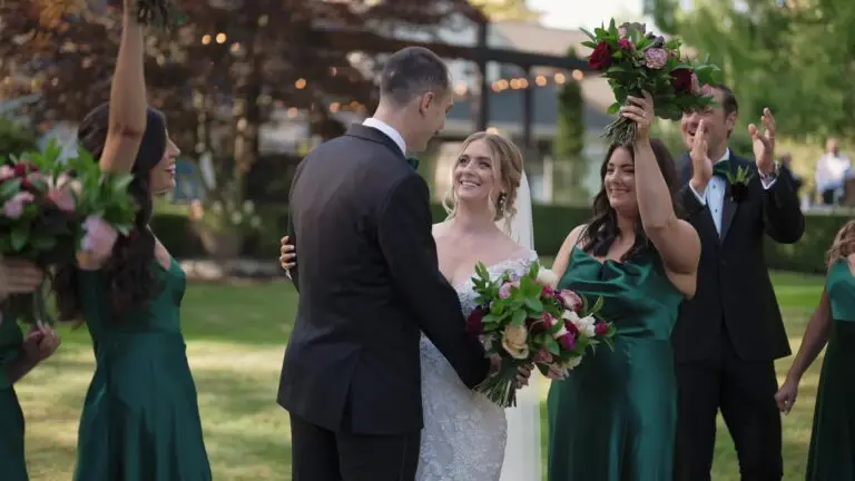 Newlyweds smiling with their wedding party outdoors