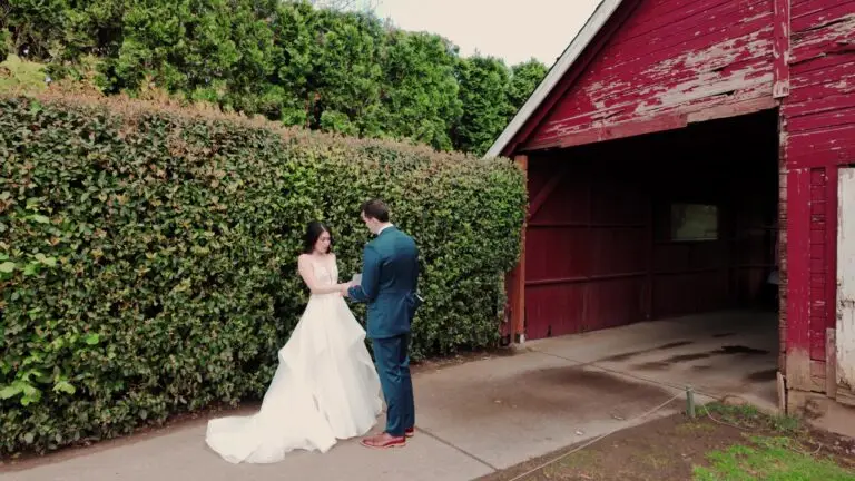 Newlyweds standing beside a red barn.