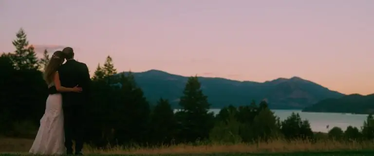 Newlyweds standing together at sunset above a river and mountains