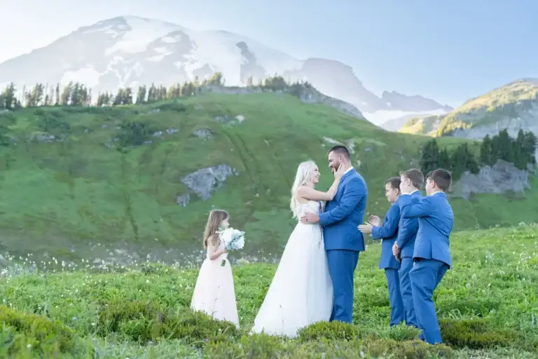 Newlyweds and children standing in a meadow below Mount Rainier