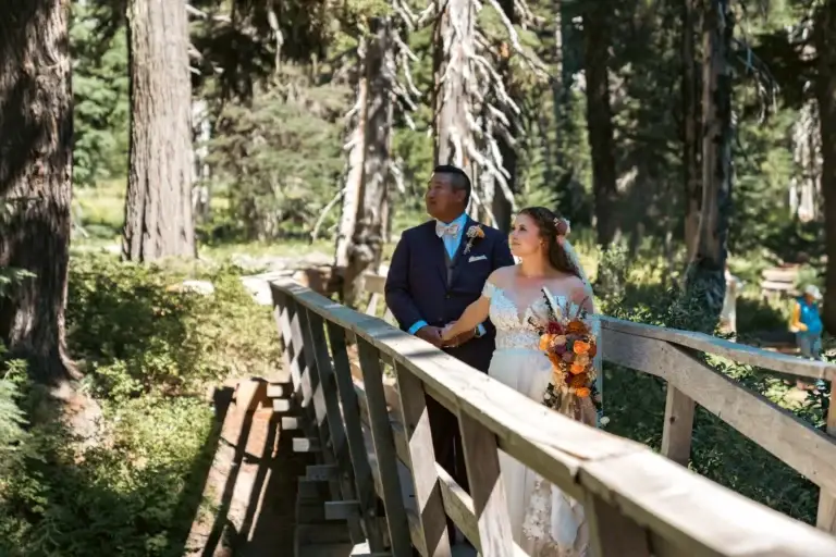 Newlyweds holding hands on a wooden bridge in a forest